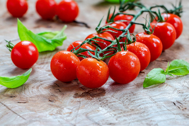 Baby tomatoes on vine on wooden table - closeup with selective focus - Foto, imagen