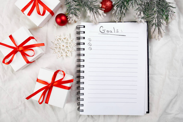 ホワイトテキスタイルリネンのテーブルクロスの背景、フラットレイアウト、コピースペース、新年の目標解像度とクリスマス装飾のための空白のノートブックのトップビュー. - 写真・画像