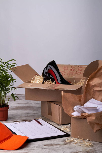 Kartons mit Schuhen, Lieferdokumenten und orangefarbener Kappe. - Foto, Bild