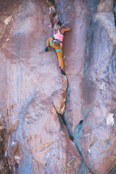 Ένας δυνατός ορειβάτης σκαρφαλώνει σε ένα βράχο, μια γυναίκα εκπαιδεύει δύναμη και αντοχή, ξεπερνώντας το φόβο των υψών, ένα κορίτσι εκπαιδεύεται σε τουρκικά βράχια.. - Φωτογραφία, εικόνα