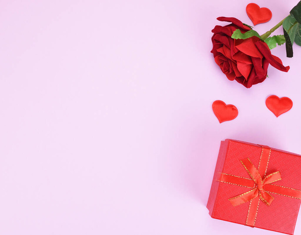 Artificial red rose bud, gift box and two decorative hearts on a pink background with a copy space. Valentine's day concept. - Foto, Bild