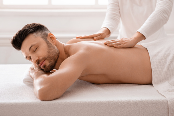 Entspannter Geschäftsmann bei Massage im Wellnessbereich nach dem Arbeitstag - Foto, Bild