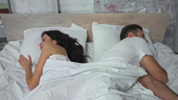 mujer preocupada mirando ofendido marido acostado en la cama - Metraje, vídeo