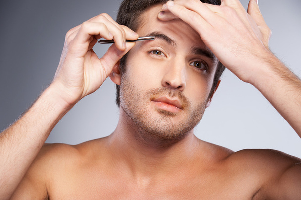 Man tweezing his eyebrows - Foto, afbeelding