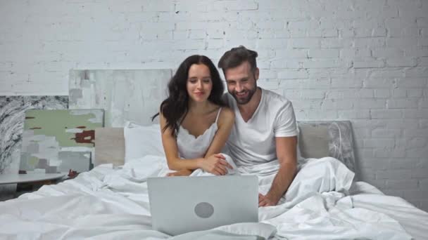 ευτυχισμένο ζευγάρι κουνώντας τα χέρια ενώ έχουν συνομιλία βίντεο στην κρεβατοκάμαρα - Πλάνα, βίντεο