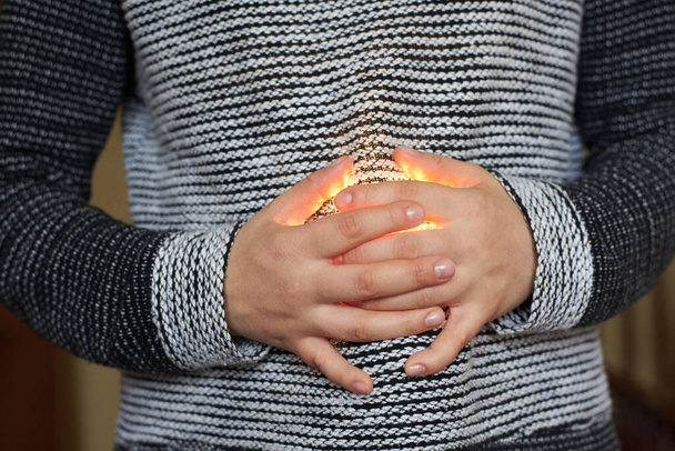 Woman holding crossed arms on belly, through which the light passes. Stomach pains. Close-up - Photo, Image