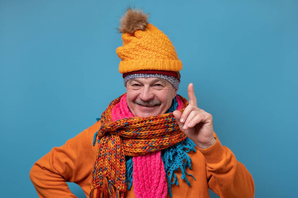 Grappige man in verschillende hoeden en sjaals wijzen omhoog geven van advies - Foto, afbeelding