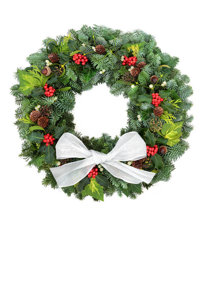 スプルースモミ、ホリー、アコーン、松のコーン、白のミステリー、弓で背景とクリスマスのための自然な冬の緑の花輪。お祝いの季節と新年のための伝統的なシンボル。スペースのコピー. - 写真・画像