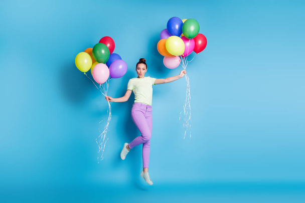 Full length body size photo of childish girl jumping high with balloons sending air kiss isolated on bright blue color background - Photo, Image
