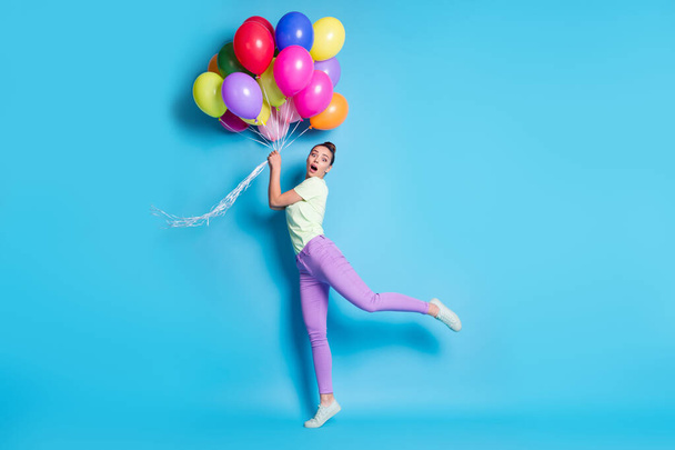Full length body size photo of surprised shocked girl funny keeping balloons on windy weather isolated on bright blue color background - Zdjęcie, obraz