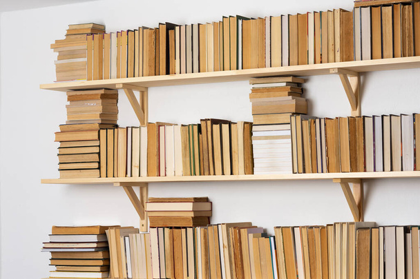 Estanterías de madera ligera con libros vueltos hacia atrás en el interior blanco, biblioteca casera - Foto, Imagen