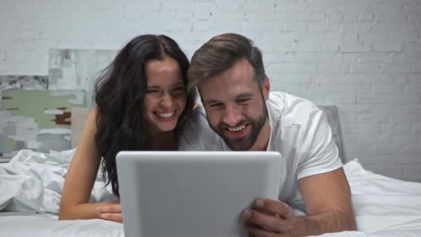 felice coppia ridendo durante la visione di film su tablet digitale  - Filmati, video