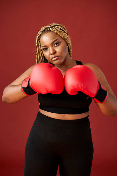 portrait of confident fat afro american woman standing with boxing gloves in fighting pose - Fotografie, Obrázek