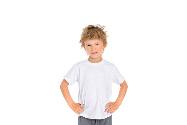 A little boy shows his displeasure with his facial expression and holding his hands at his waist. Photo of a boy on a white background. - Foto, Bild