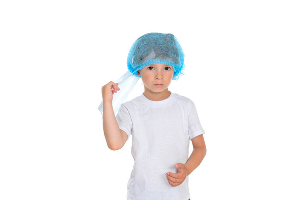 The boy removes the protective mask from his face, showing that he no longer needs it. Photo of a boy on a white isolated background, the boy is dressed in a plain white t-shirt. - Photo, image