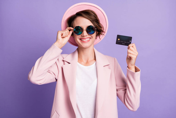 Photo of curly cute cheerful woman wear casual vintage blazer glasses holding wireless credit card arm glasses isolated purple color background - Fotografie, Obrázek
