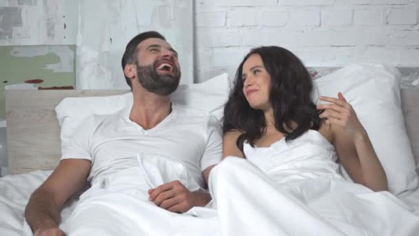 fröhliche Frau im Gespräch mit glücklichem Ehemann stößt Kopf im Schlafzimmer  - Filmmaterial, Video