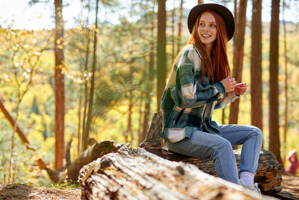side view on positive redhead woman looking away in the forest - Foto, Bild