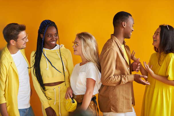 stylish mixed race youth talking, smiling isolated on yellow background - Фото, изображение