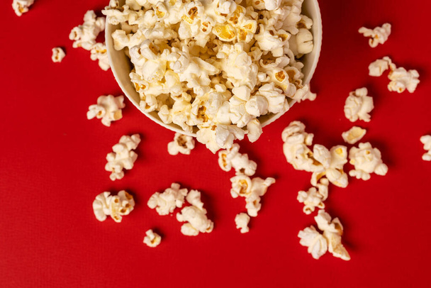 A bowl of popcorn on a red background, photo taken from above. - Photo, Image