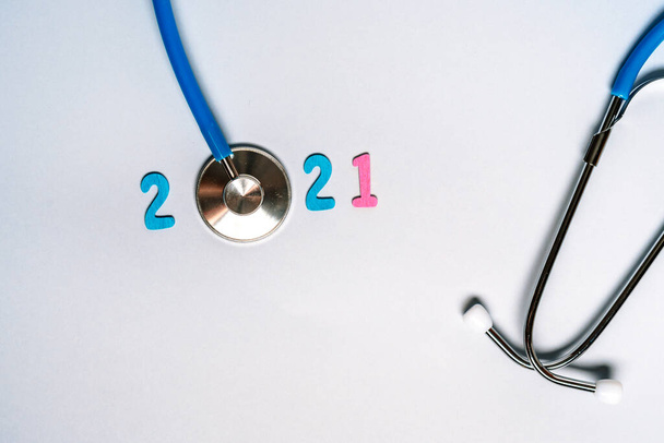 Stetoscopio con i numeri 2021 su sfondo blu. Natale per lo striscione sanitario e medico o la copertina del calendario. Idea creativa. - Foto, immagini