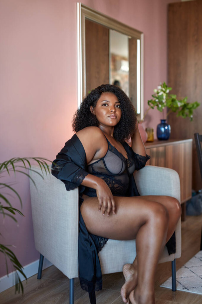 beautiful african plus size model sits on chair at home, have rest - Fotografie, Obrázek