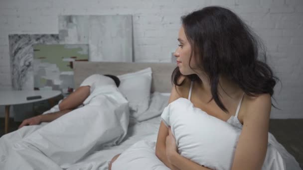 θλιμμένη γυναίκα να κάθεται στο κρεβάτι και να πετάει μαξιλάρι στον κοιμισμένο σύζυγο  - Πλάνα, βίντεο