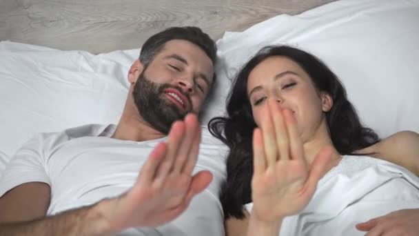 ευτυχισμένο ζευγάρι ξαπλωμένο στο κρεβάτι και παίζοντας πέτρα ψαλίδι χαρτί παιχνίδι - Πλάνα, βίντεο