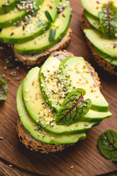 Avocado toasts with hemp seeds on a wooden background, top view - Фото, изображение