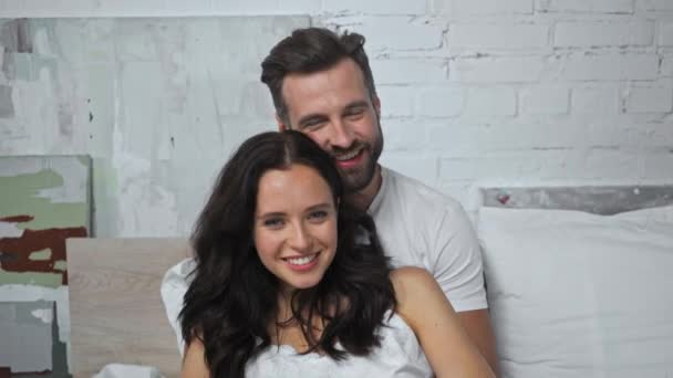 glücklicher Mann umarmt freudige Frau im Schlafzimmer  - Filmmaterial, Video