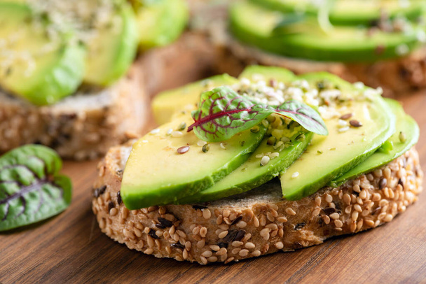 Healthy vegan avocado toast with hemp seeds on a wooden table background, closeup view - 写真・画像
