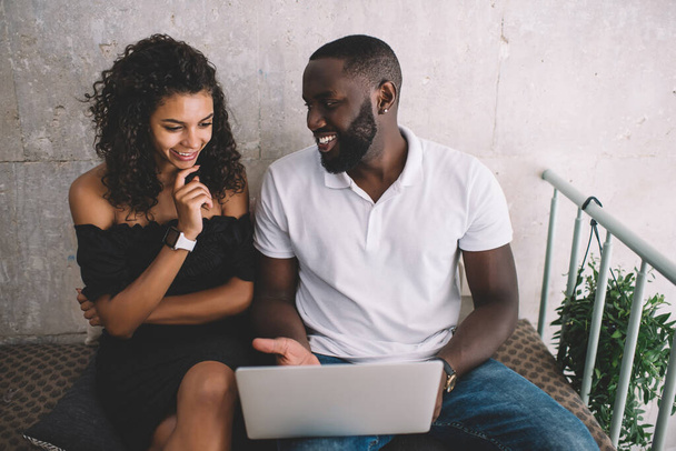 From above of African American male and female business partners in casual wear enjoying work together with laptop in modern cafe - Фото, изображение