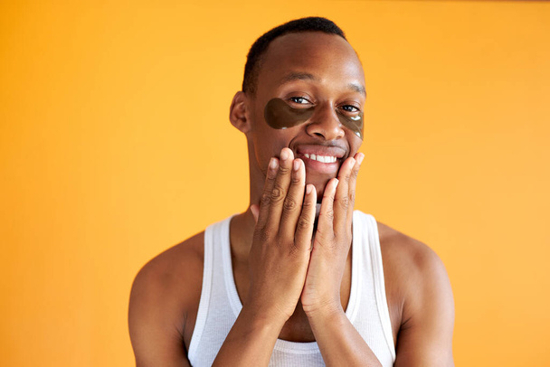 portrait of smiling african american man with black hydrogel patches under eyes - Foto, Imagen