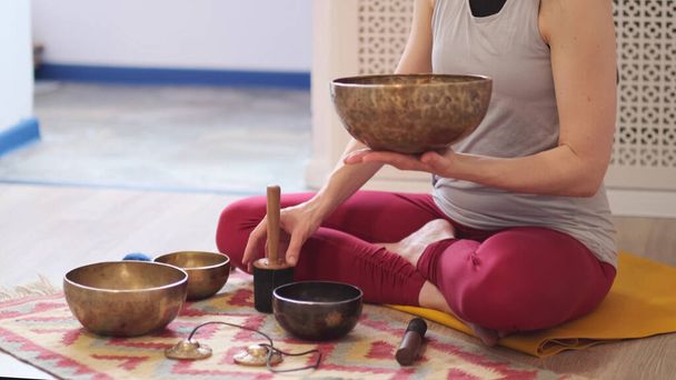 Жінка грає на тибетській співочій чаші, сидячи на йога маті. Вінтаж тонований. - Фото, зображення