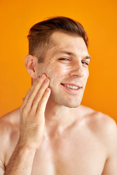 young caucasian man apply moisturizing face cream for healthy glowing skin, isolated - Φωτογραφία, εικόνα