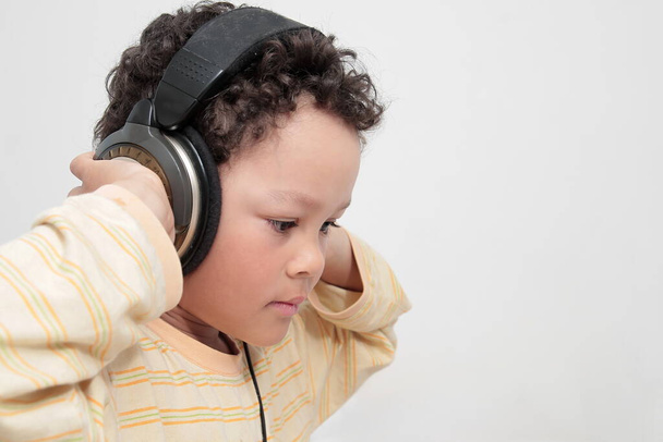 Kind mit Kopfhörern genießt Musik auf weißem Hintergrund Archivfoto   - Foto, Bild