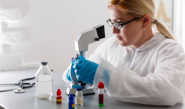 A beautiful female medical or scientific researcher using her microscope in a laboratory. - Zdjęcie, obraz