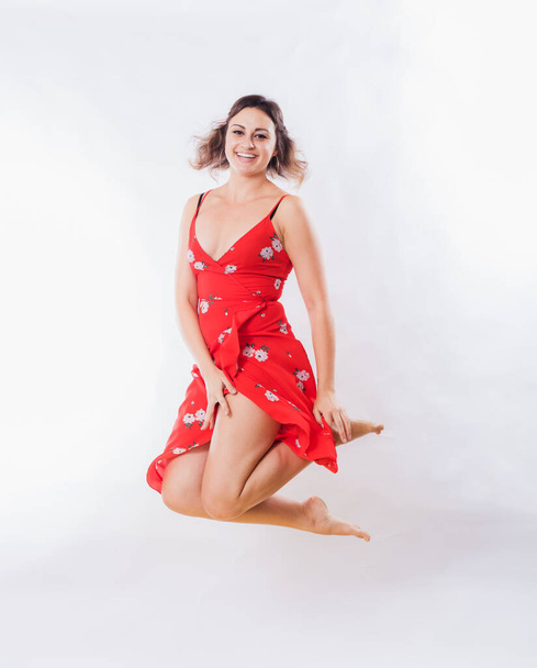 Beautiful young woman in red dress jumping - Фото, зображення