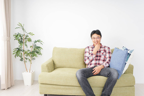 feliz asiático homem sentado no sofá em casa  - Foto, Imagem
