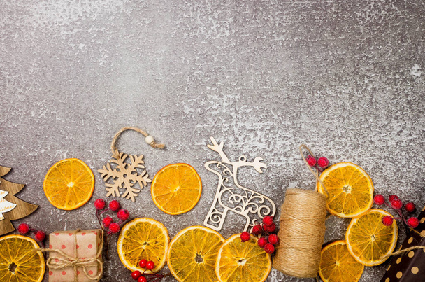 Christmas set with gifts wrapped in craft paper, wooden toys for christmas tree, dry oranges on light grey background. New Year's or winter Eve composition. Christmas time concept. Greeting card, - Photo, Image