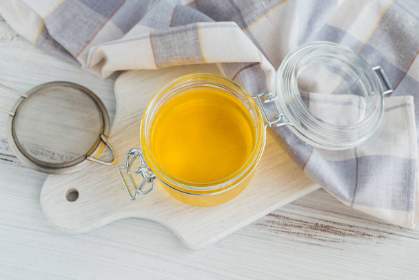 Homemade Ghee or clarified butter in jar on white wooden table. - Φωτογραφία, εικόνα