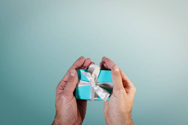 mani in possesso di una scatola regalo turchese legato con nastro di seta bianca - Foto, immagini