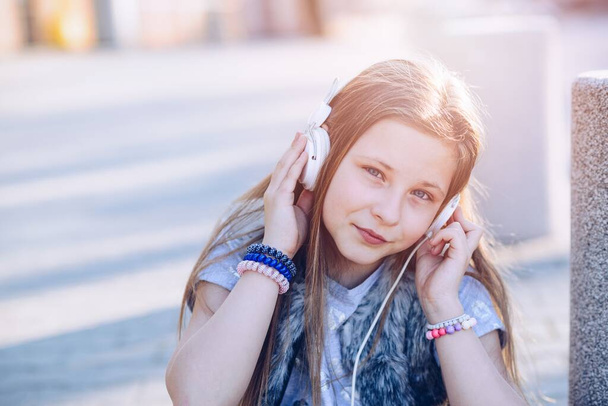 Mietteliäs tyttö sinisilmäinen kuuntelee musiikkia kuulokkeilla. - Valokuva, kuva