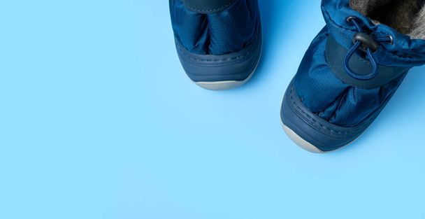 Botas cálidas azules de invierno para recién nacidos sobre fondo azul claro espacio plano de copia laica. Zapatos pequeños para niños. Botas de invierno de tela de moda con suelas de goma. Moda infantil. Botas para chico. - Foto, imagen