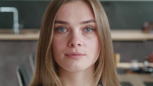 Közelkép vonzó fiatal európai nő modell nézi kamera otthon. Portré, ha gyönyörű női profi csinos arccal és kék szemekkel áll egyedül a házban - Felvétel, videó