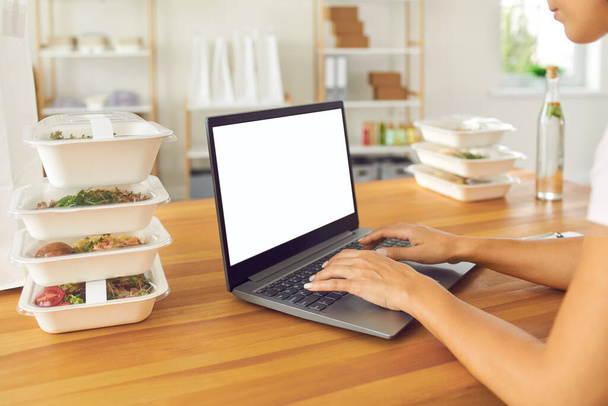 Jonge vrouw voedsel bezorger communiceren online en het accepteren van orders voor gezonde maaltijden - Foto, afbeelding