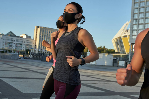 Young caucasian fit people in protective masks running - Photo, image