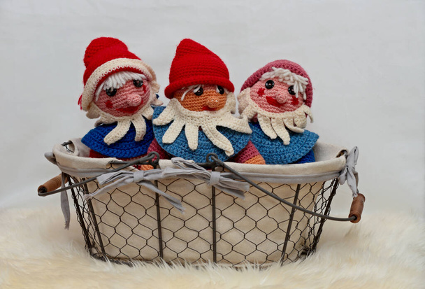 Three self made crocheted colorful gnomes in basket with white background - Photo, Image