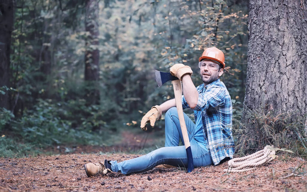 Male lumberjack in the forest. Professional woodcutter inspects trees for felling. - Фото, зображення