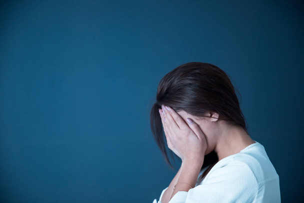 sad woman hand in face on blue backgroun - Фото, изображение